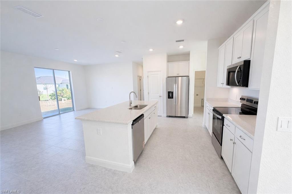 Kitchen featuring stainless steel appliances, white cabinets, a center island with sink, recessed lighting, and open floor plan
