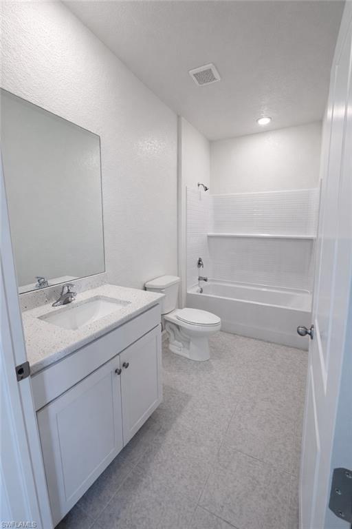 Full bath with vanity,  shower combination, a textured wall, and a textured ceiling