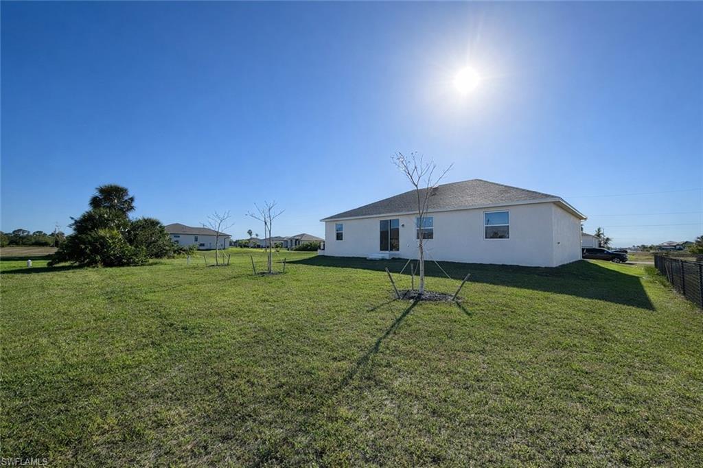 Back of house with stucco siding and a lawn