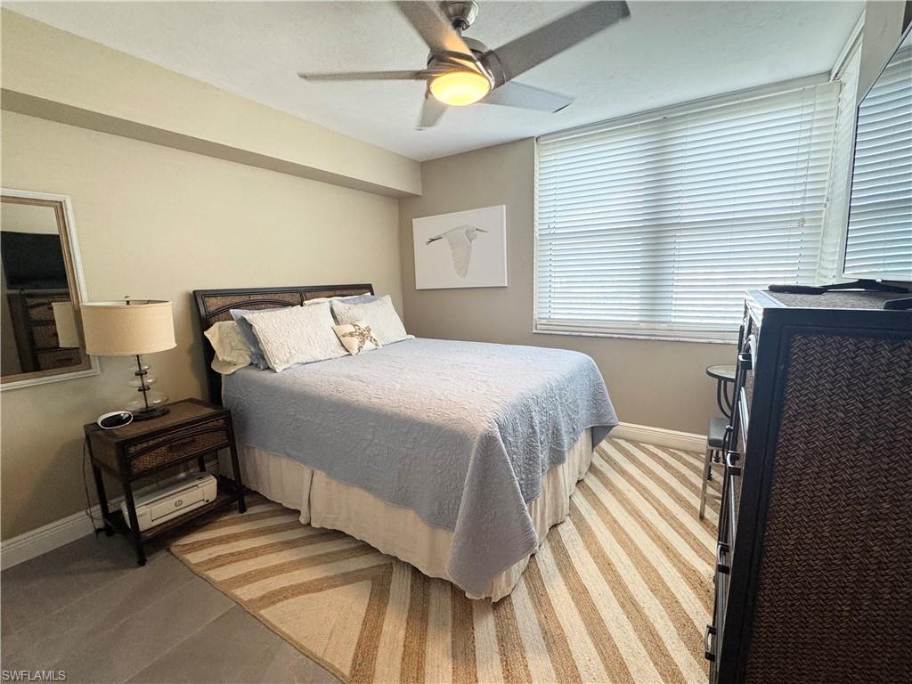 Bedroom featuring tile, baseboards , an area rug and ceiling fan