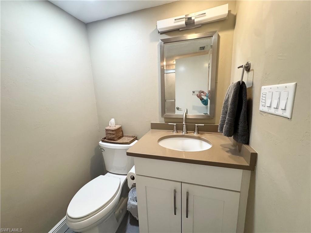 Half bath featuring vanity and a textured wall