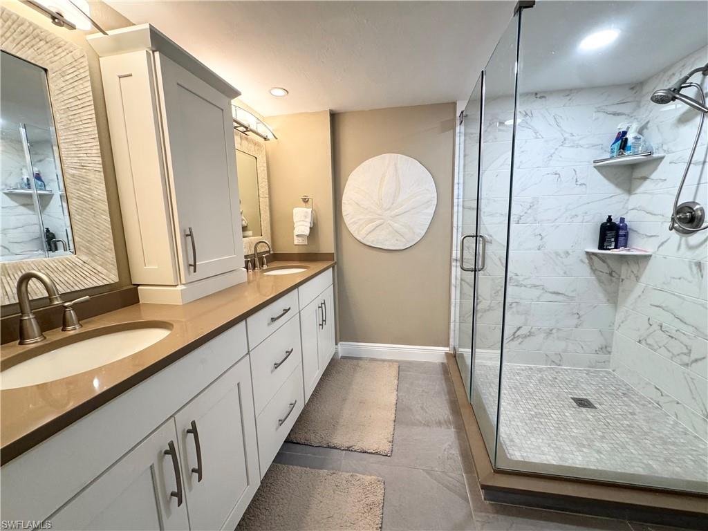 Full bath featuring double vanity, a marble finish shower, and recessed lighting