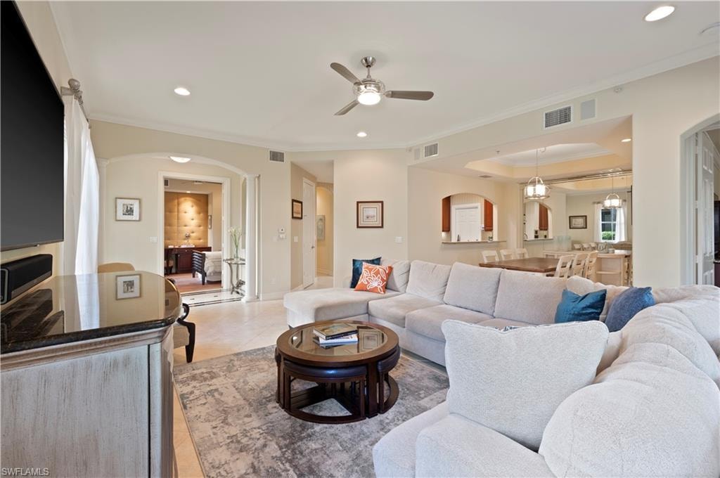 Living room featuring arched walkways, crown molding, recessed lighting, ceiling fan, and light tile patterned floors
