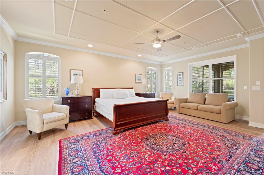 Bedroom featuring light wood-type flooring, a ceiling fan, multiple windows, and crown molding
