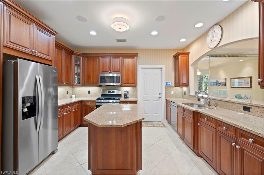 Kitchen featuring stainless steel appliances, light stone countertops, brown cabinetry, and recessed lighting