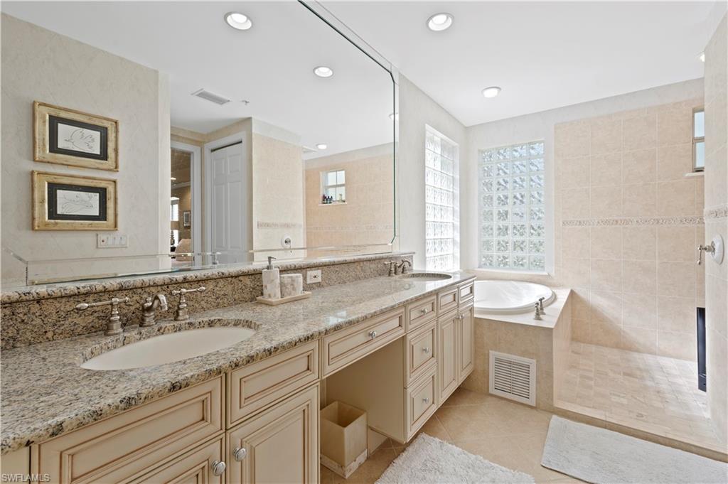 Bathroom featuring double vanity, light tile patterned floors, a bath, walk in shower, and recessed lighting
