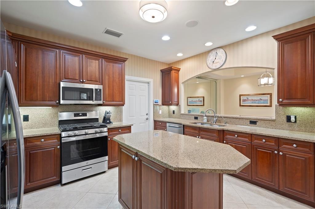 Kitchen with stainless steel appliances, light stone counters, light tile patterned floors, recessed lighting, and a kitchen island