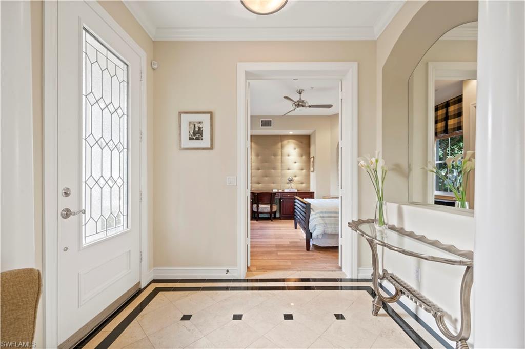 Foyer featuring inlaid floor details, light tile patterned flooring, crown molding, and ceiling fan