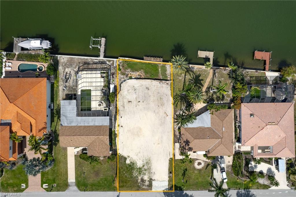 Aerial perspective of suburban area with property boundaries highlighted and a nearby body of water