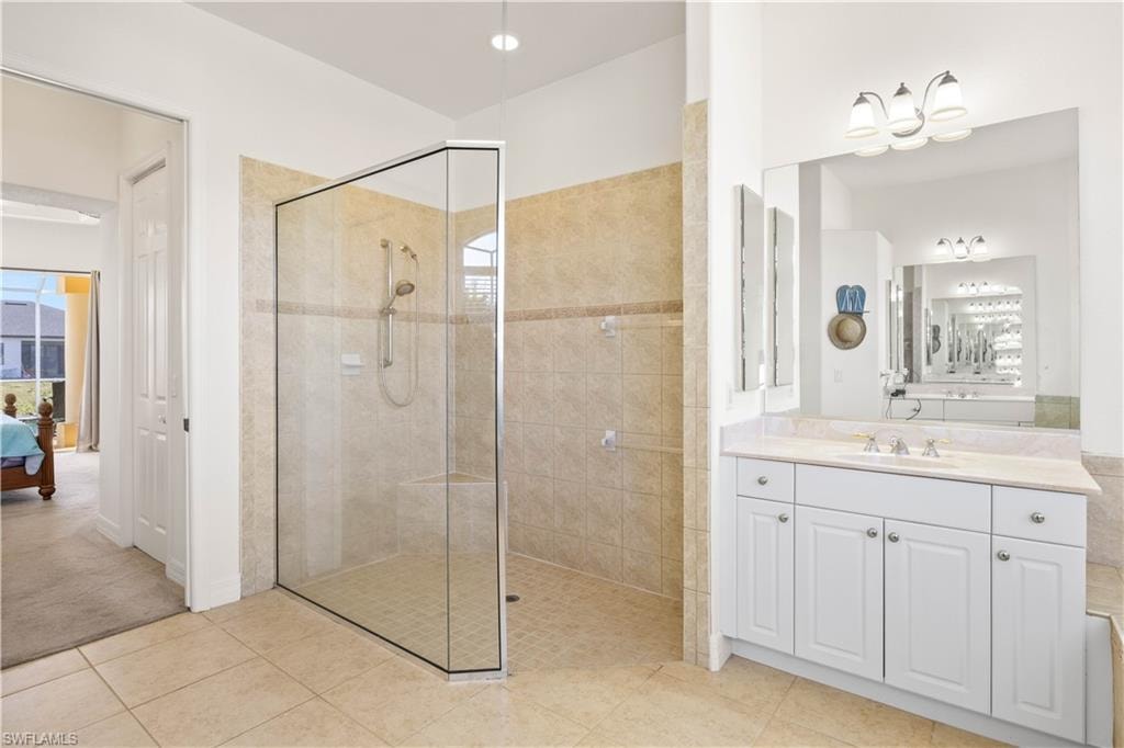 Ensuite bathroom featuring a stall shower, vanity, and light tile patterned floors