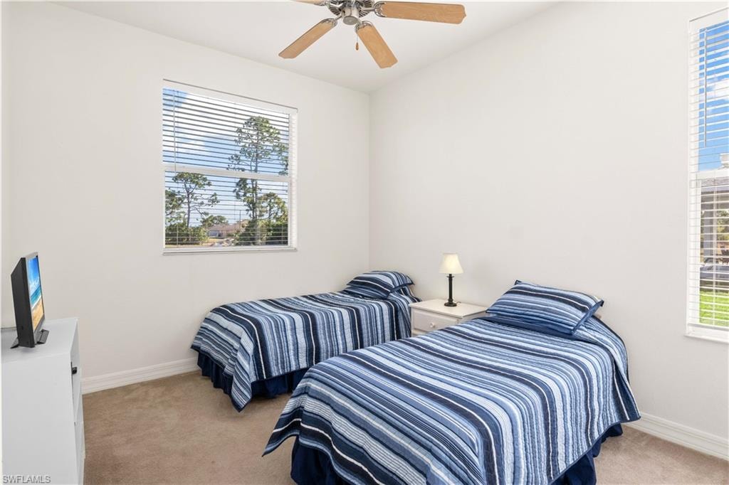 Bedroom featuring light carpet, multiple windows, and ceiling fan