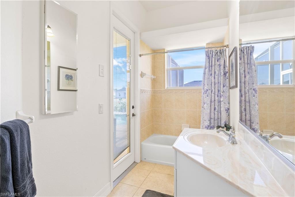 Full bath featuring shower / tub combo, vanity, plenty of natural light, and light tile patterned floors