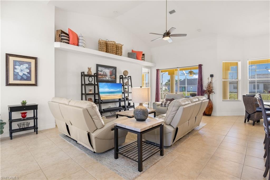 Living area with light tile patterned flooring, high vaulted ceiling, and ceiling fan