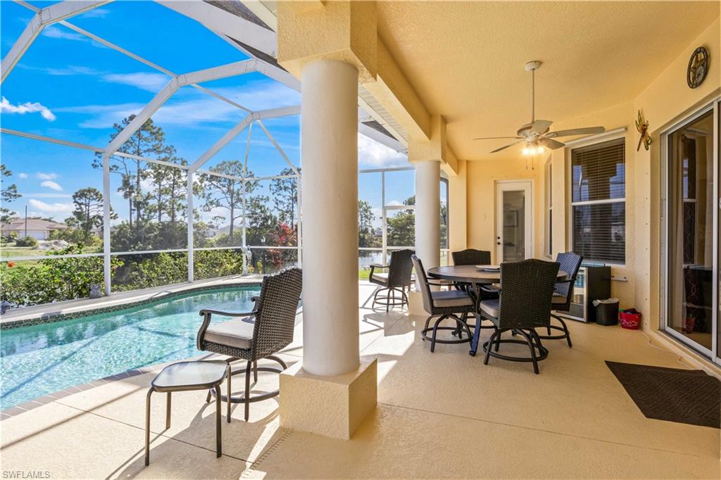 View of patio with a sunroom, ceiling fan, an outdoor pool, glass enclosure, and outdoor dining space