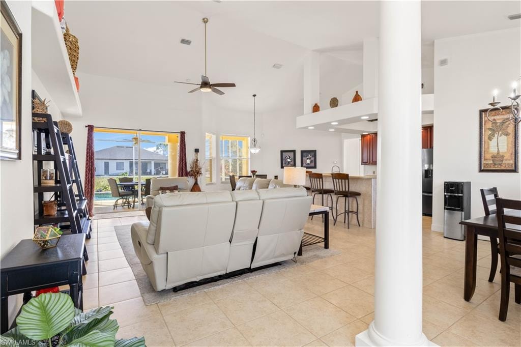 Living room featuring high vaulted ceiling, light tile patterned flooring, and ceiling fan