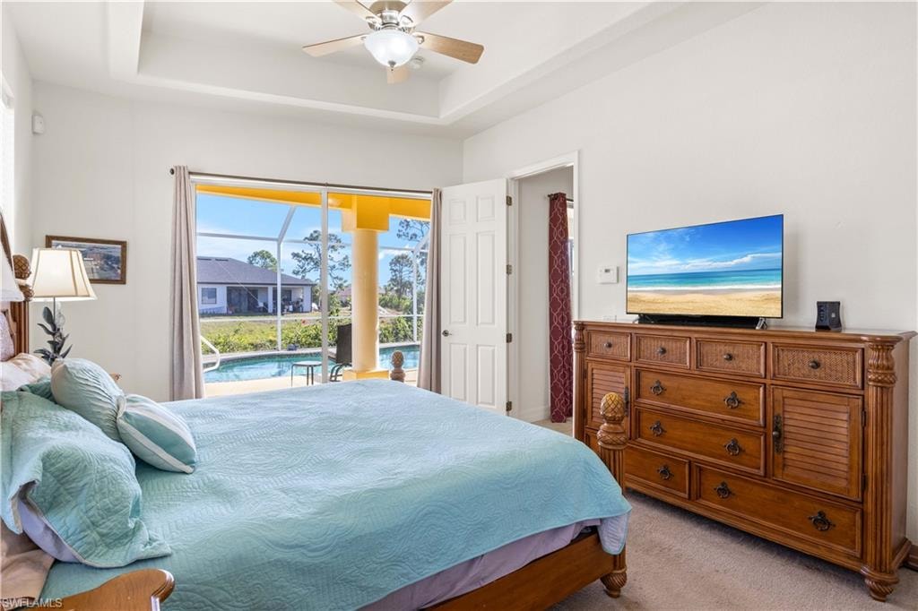 Bedroom featuring a sunroom, access to outside, carpet floors, a raised ceiling, and ceiling fan