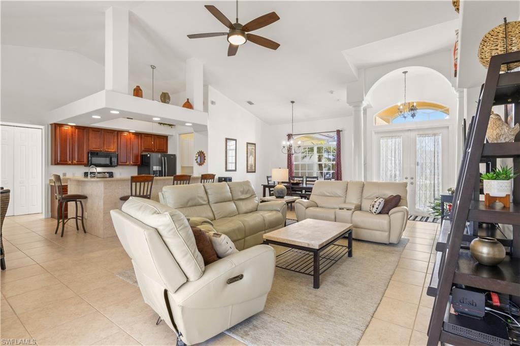 Living area featuring high vaulted ceiling, a ceiling fan, a chandelier, and light tile patterned floors