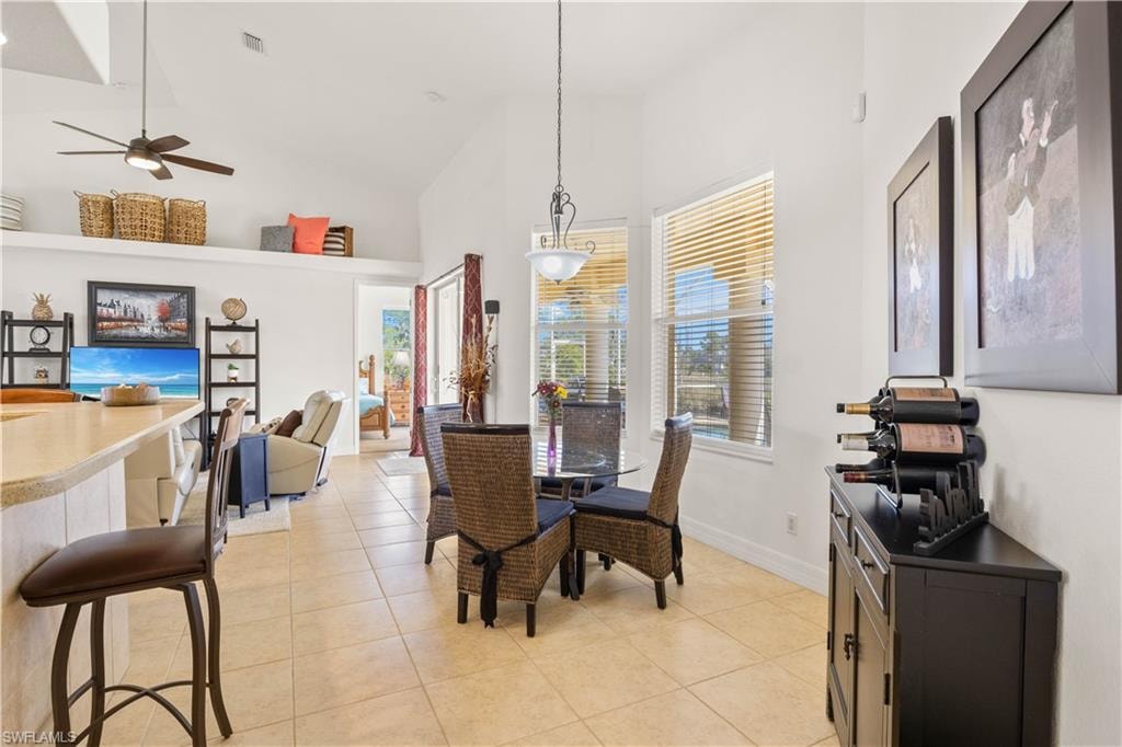 Dining space with high vaulted ceiling, light tile patterned floors, and ceiling fan