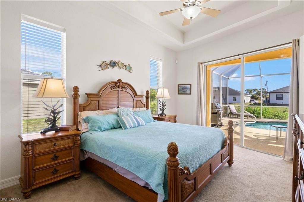 Carpeted bedroom with ceiling fan, access to exterior, multiple windows, and a sunroom
