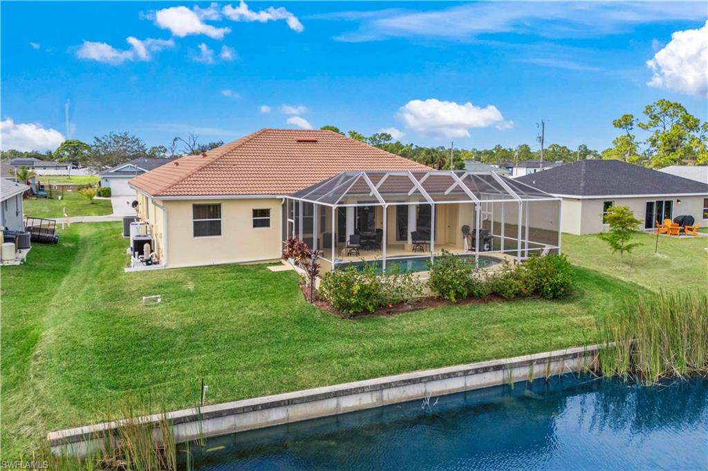 Rear view of house with a lanai, a yard, a water view, a sunroom, and an outdoor pool