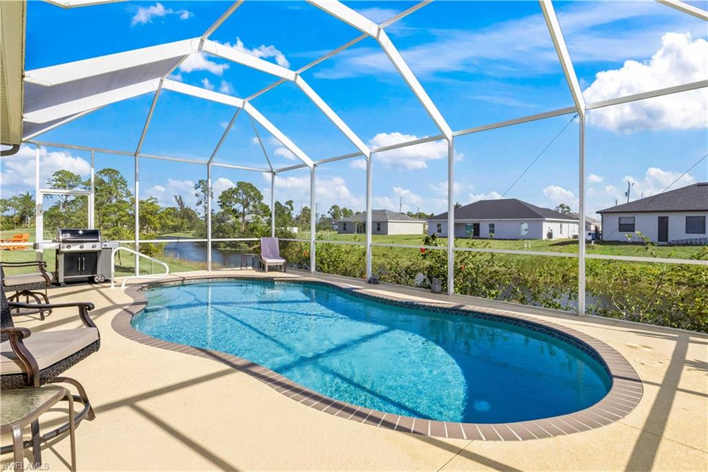 Outdoor pool featuring a lanai, a sunroom, a grill, and a patio area