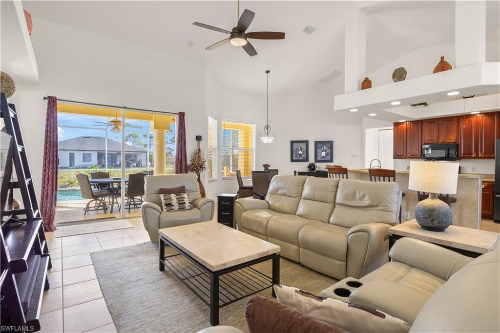 Living room with light tile patterned floors, high vaulted ceiling, and ceiling fan