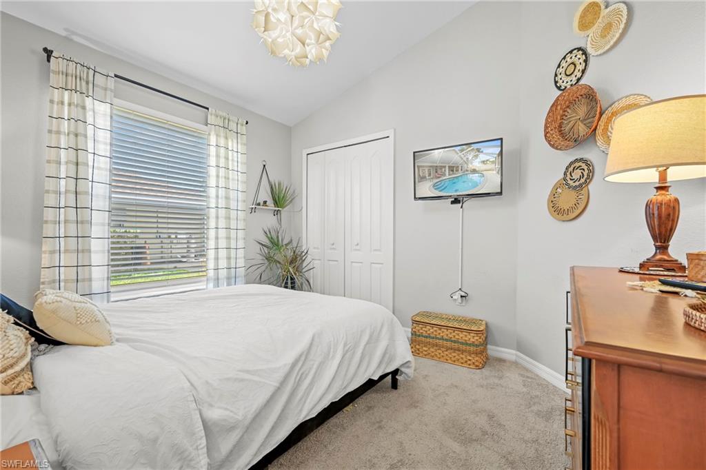 Bedroom with lofted ceiling, light carpet, a closet, and a chandelier