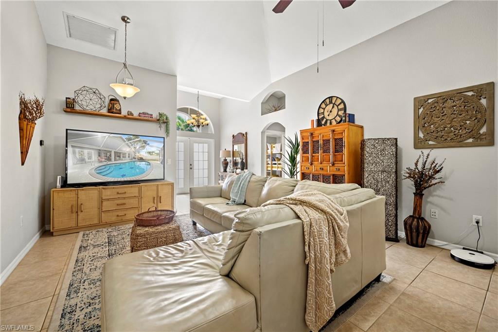 Living area featuring high vaulted ceiling, light tile patterned flooring, a ceiling fan, and arched walkways