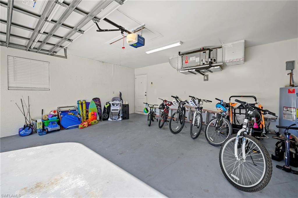 Garage featuring electric water heater and a garage door opener