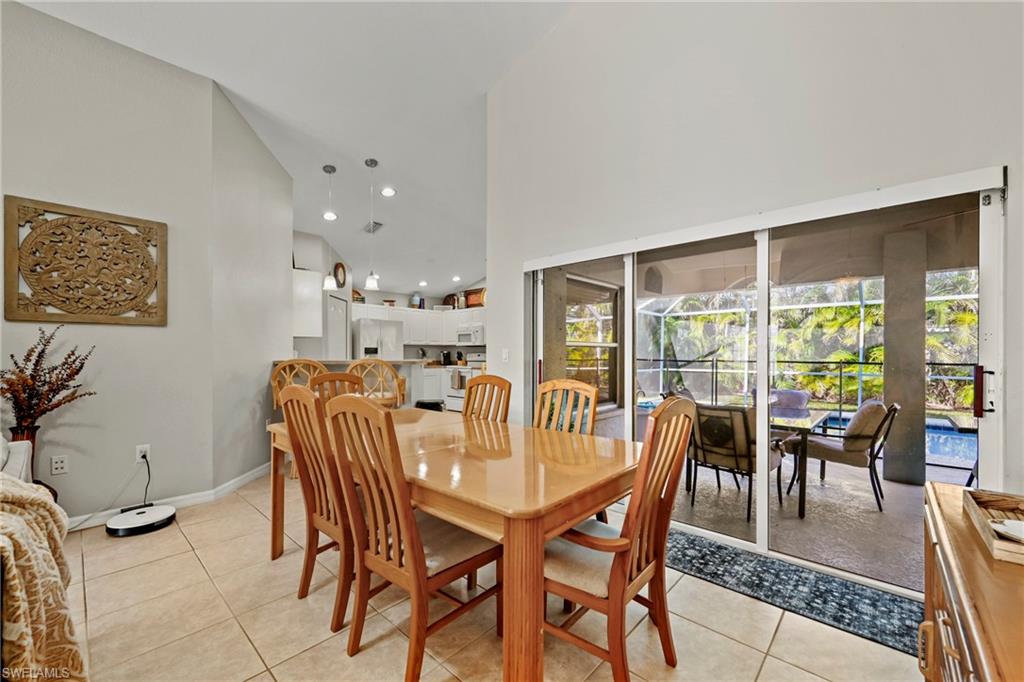 Dining space featuring french doors, arched walkways, vaulted ceiling, a ceiling fan, and light tile patterned flooring