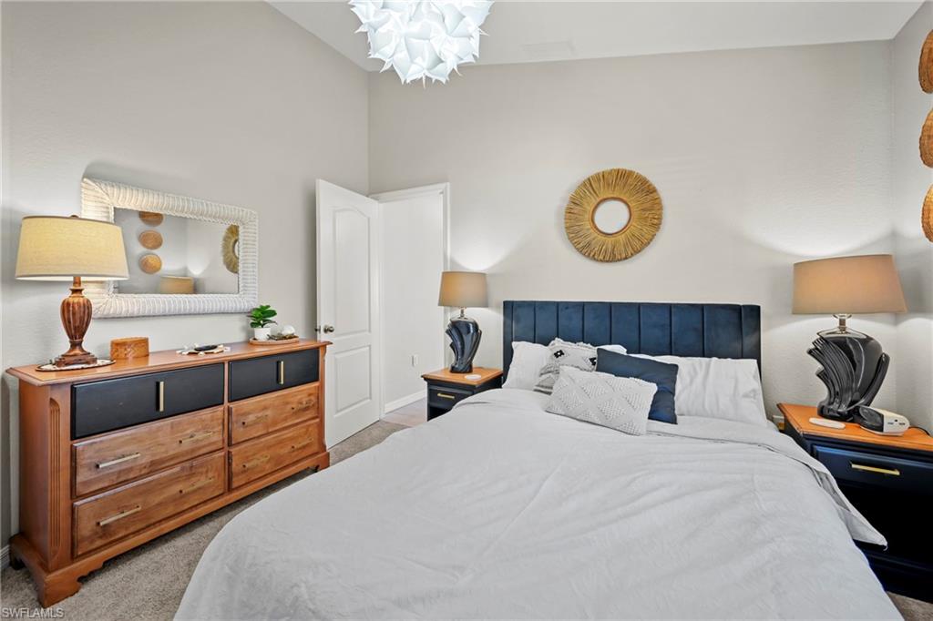 Bedroom featuring light colored carpet and high vaulted ceiling