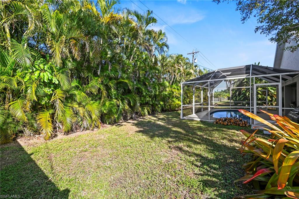 View of green lawn with a lanai, an outdoor pool, a sunroom, and a patio area
