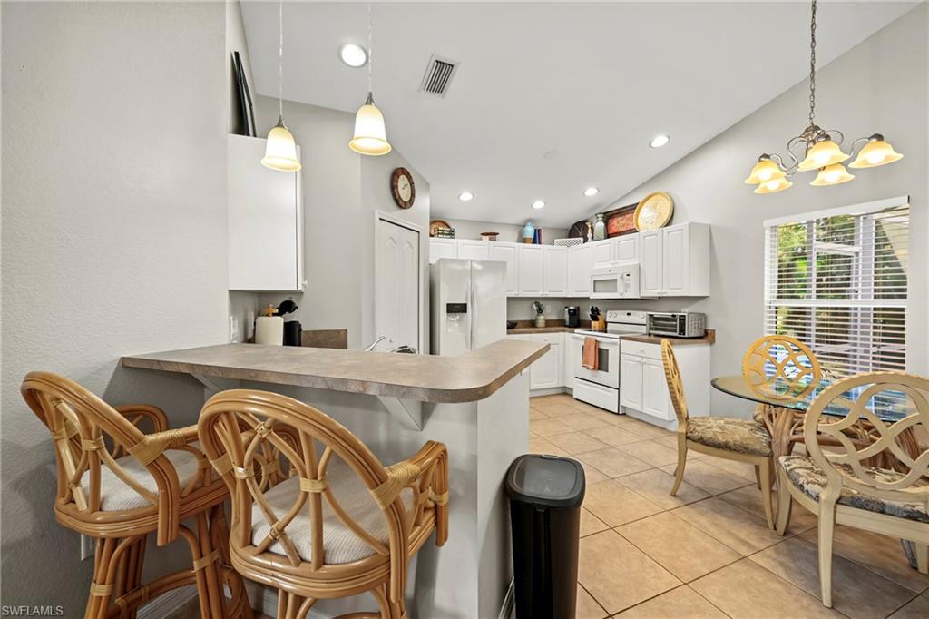 Dining space featuring high vaulted ceiling, light tile patterned floors, and recessed lighting