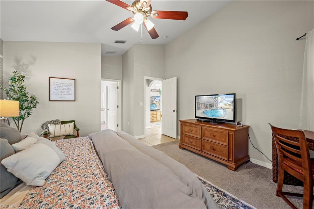 Bedroom featuring an office area, vaulted ceiling, french doors, access to exterior, and light colored carpet