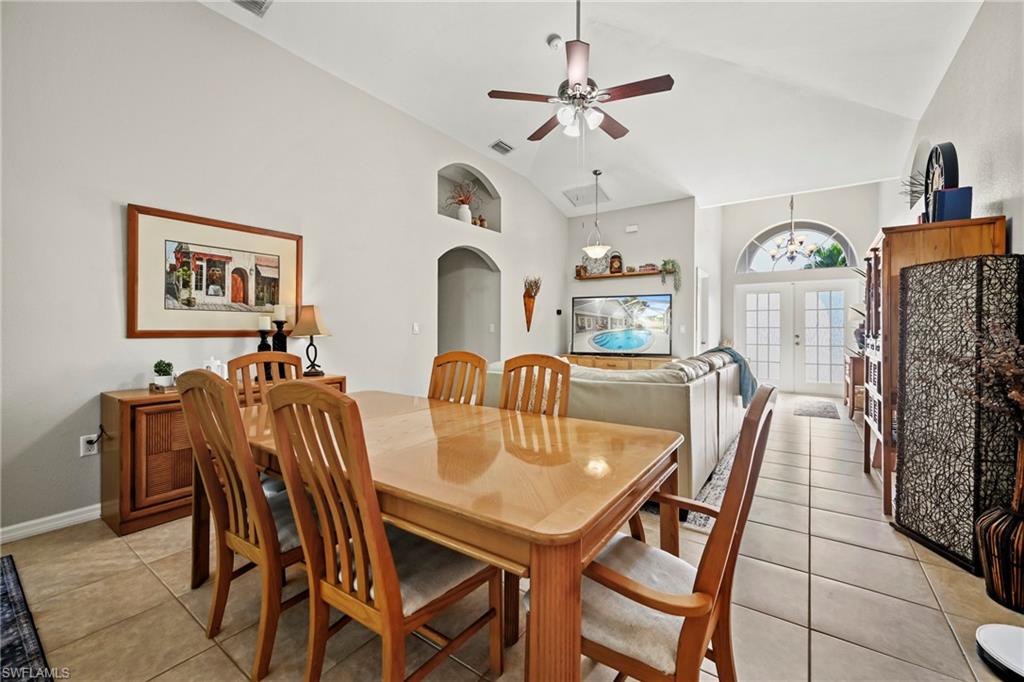 Living room with french doors, a ceiling fan, arched walkways, light tile patterned flooring, and high vaulted ceiling