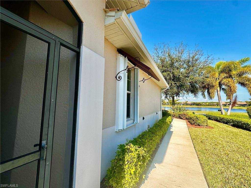 View of property exterior featuring a lawn, stucco siding, and a water view