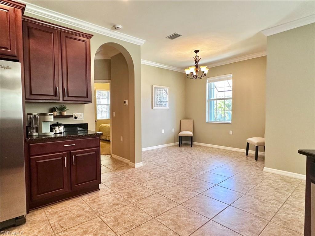 Kitchen with arched walkways, dark stone counters, plenty of natural light, freestanding refrigerator, and ornamental molding