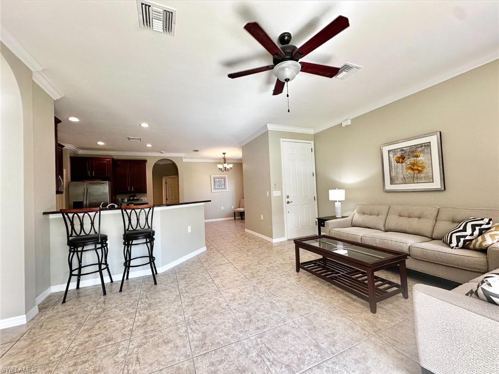 Living area with arched walkways, ornamental molding, a ceiling fan, recessed lighting, and light tile patterned flooring