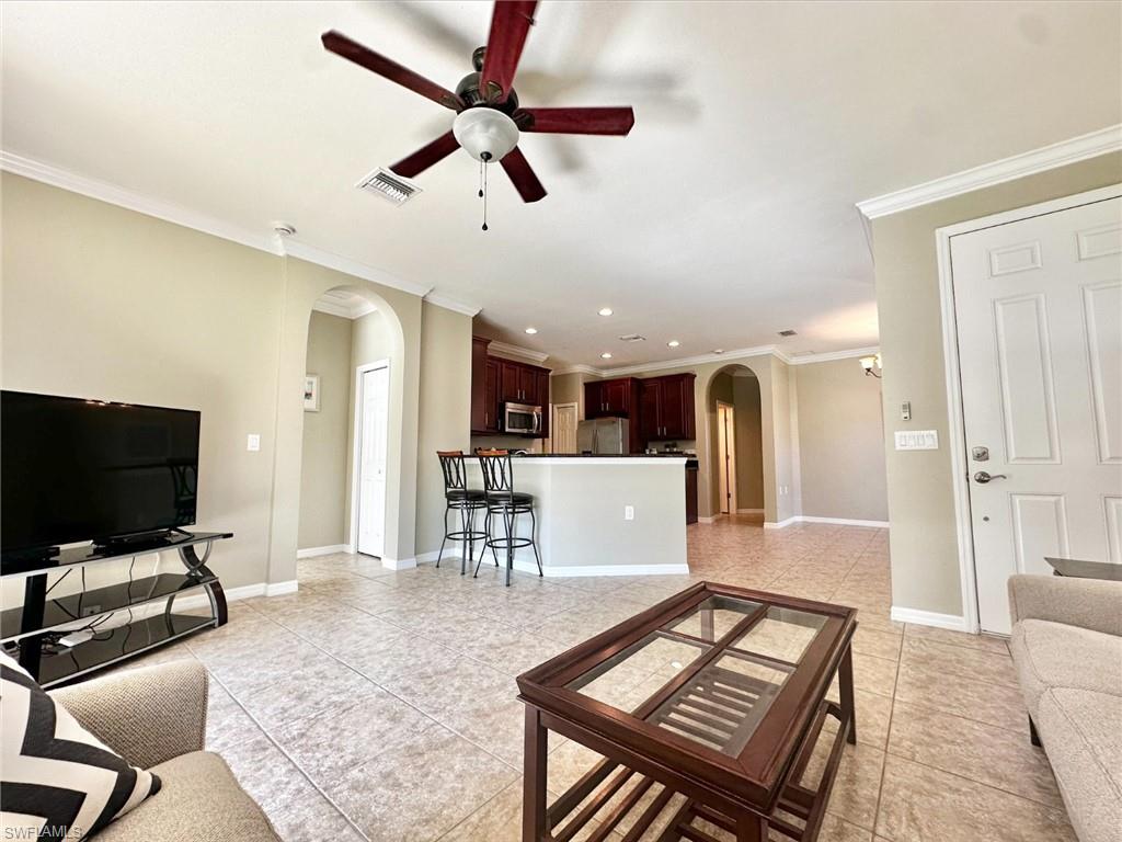 Living area featuring arched walkways, ornamental molding, a ceiling fan, light tile patterned floors, and recessed lighting