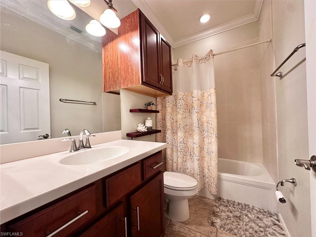 Full bath featuring shower / bath combo, vanity, ornamental molding, and light tile patterned flooring