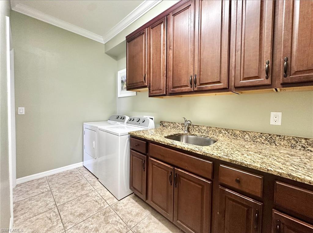 Laundry room with crown molding, cabinet space, independent washer and dryer, and light tile patterned floors
