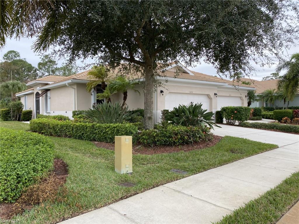Single story home featuring stucco siding, driveway, a tiled roof, an attached garage, and a front lawn