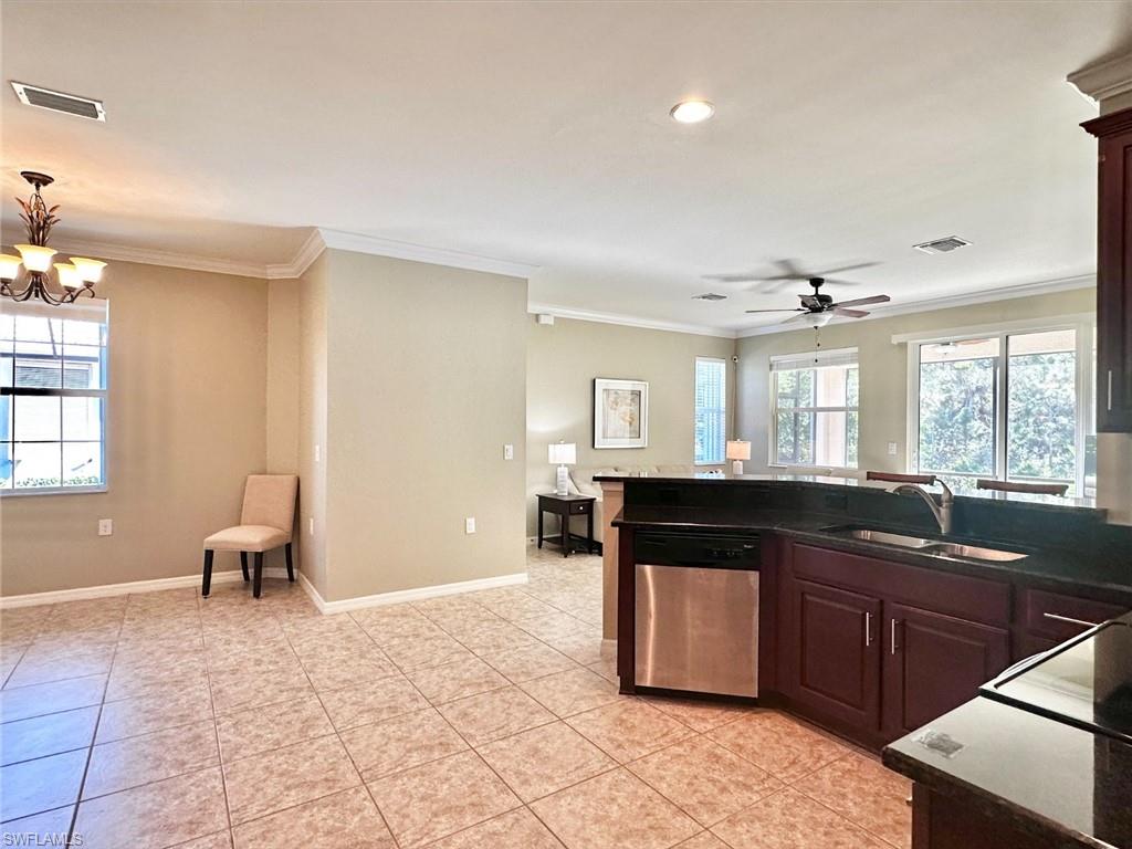 Kitchen with stainless steel dishwasher, healthy amount of natural light, crown molding, open floor plan, and a peninsula
