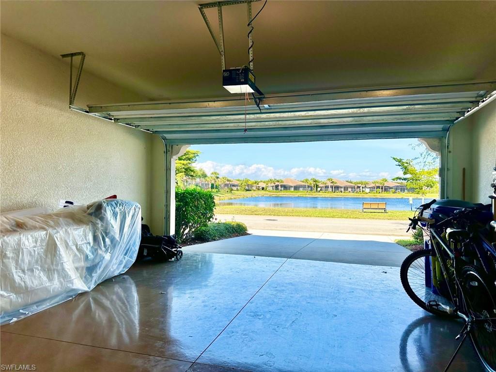 Garage with a water view, a garage door opener, a textured wall, and a residential view