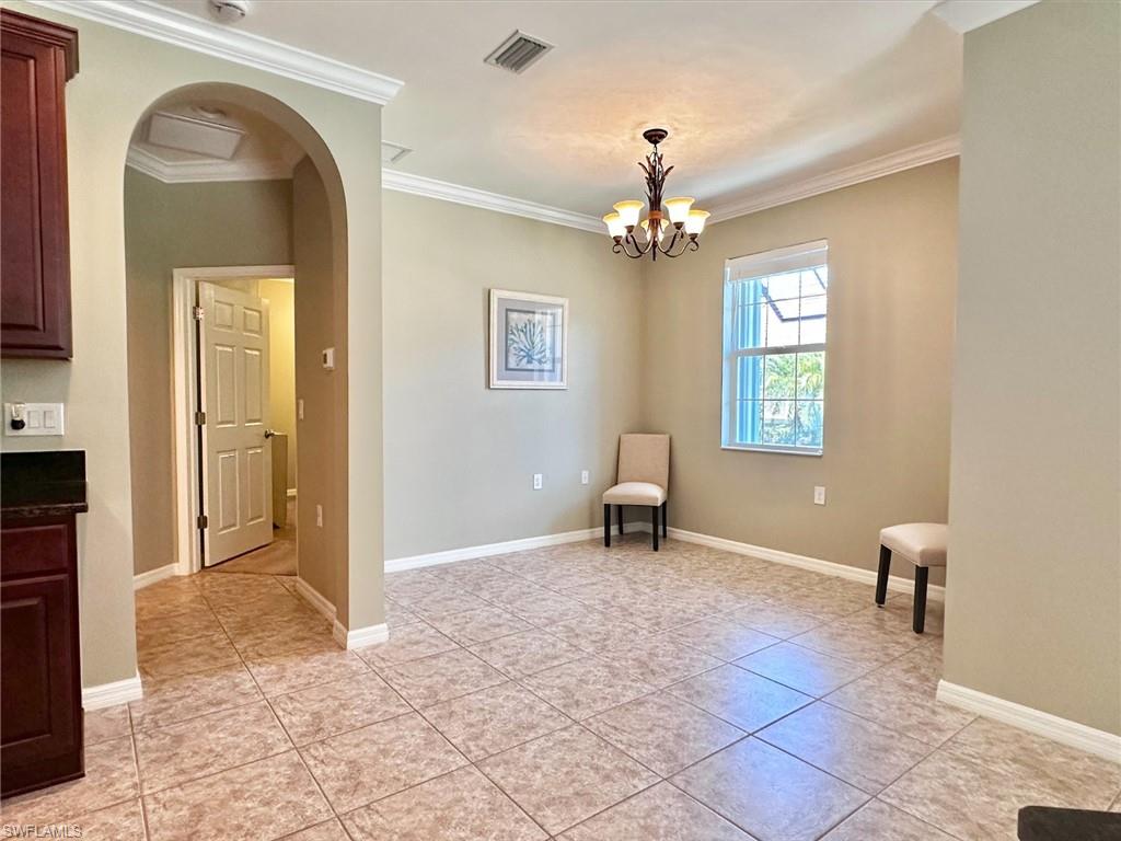 Unfurnished room with arched walkways, crown molding, light tile patterned floors, and a chandelier