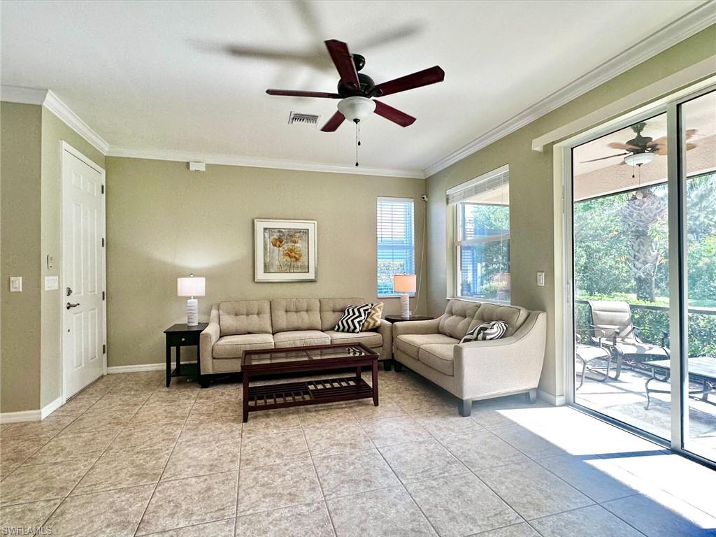 Living room with crown molding, ceiling fan, and light tile patterned floors