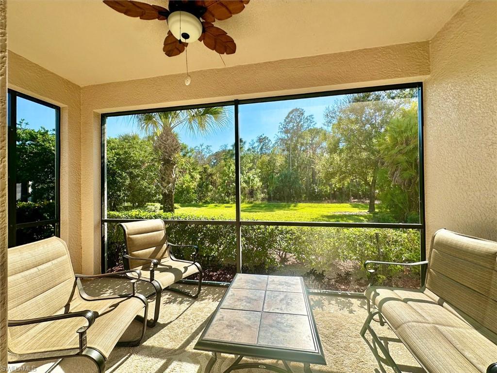 Sunroom / solarium featuring a ceiling fan, view of wooded area, and healthy amount of natural light