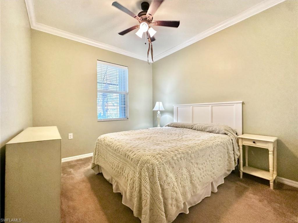 Carpeted bedroom with ornamental molding and a ceiling fan