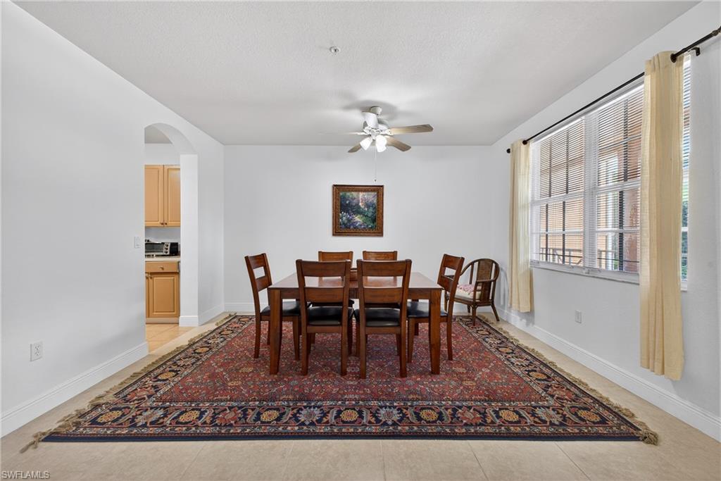 Dining room featuring arched walkways, a ceiling fan, and light tile patterned flooring