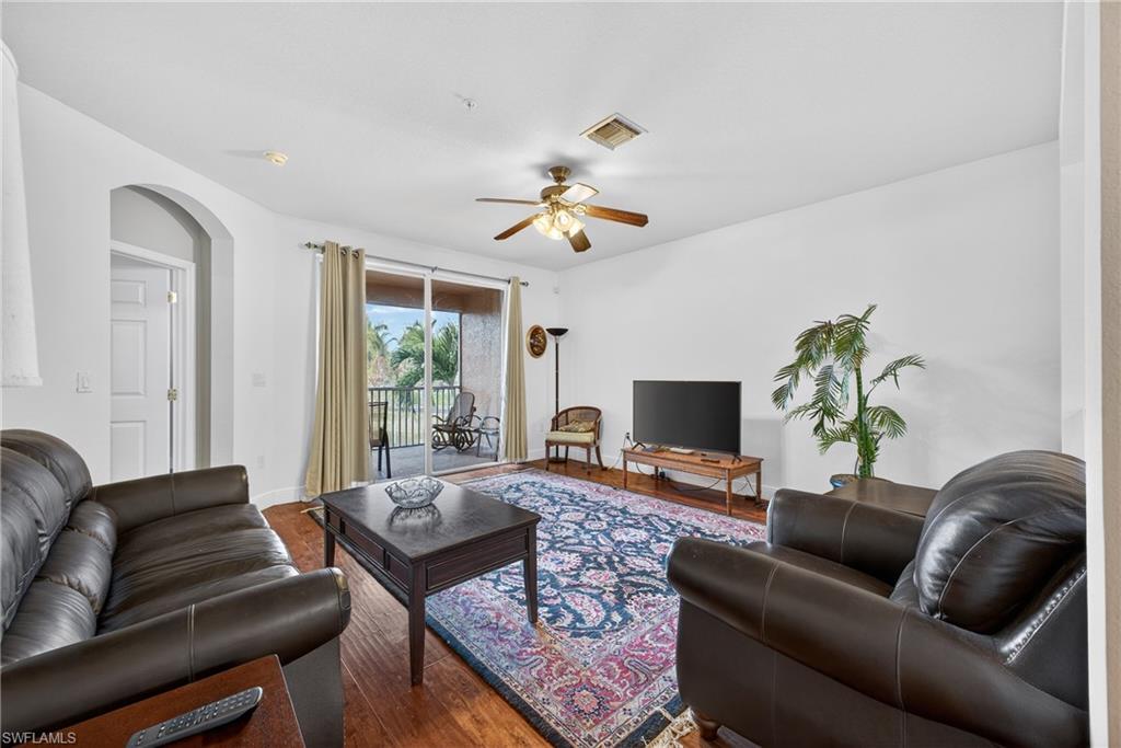Living area with wood finished floors, a ceiling fan, and arched walkways